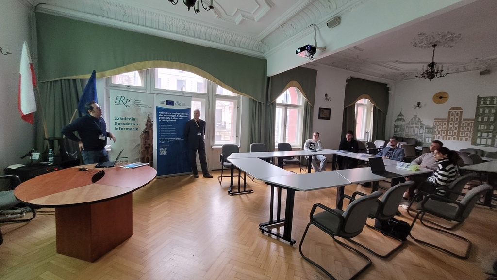 wizja lokalna w FRP 6.03.2024 - pracownicy FRP prowadzą prelekcję dla grupy studentów EkSocu siedzących przy stole