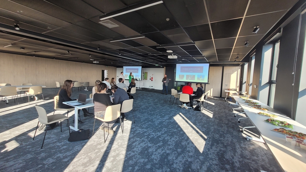 wizja lokalna studentów EkSocu w Nordei 20.03.2024 - trzech pracowników firmy prowadzi prelekcję przed grupą studentów siedzących przy stolikach