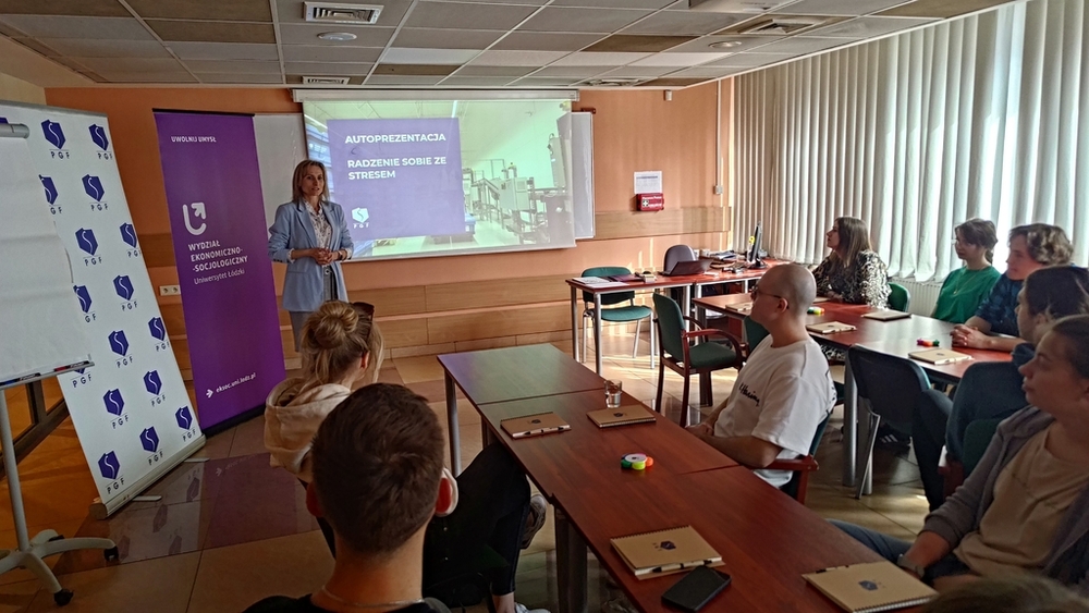 szkolenie pt. Autoprezentacja i radzenie sobie ze stresem - Polska Grupa Farmaceutyczna - 14.04.2025 - studenci siedzą przy stołach i słuchają Prowadzącej szkolenie